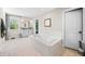 Bright bathroom features a soaking tub with white tile surround, a window, and a vanity with drawers and countertop space at 5990 Hollow Ct, Bargersville, IN 46106