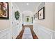 Long hallway with wood floors, white wainscoting, and decorative accents leading to the front door at 5990 Hollow Ct, Bargersville, IN 46106
