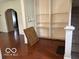 A spacious room featuring hardwood floors, an archway, built-in shelving, and stair access at 616 N Exeter Ave, Indianapolis, IN 46222