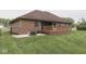 Backyard featuring a brick house, wood deck, fire pit, and green grass at 6494 N Baltimore Rd, Monrovia, IN 46157