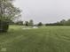 Scenic view of a pond surrounded by a well-maintained lawn and mature trees in a large backyard at 6494 N Baltimore Rd, Monrovia, IN 46157