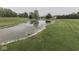 Close-up of a pond with a rock-lined edge, surrounded by a well-manicured lawn at 6494 N Baltimore Rd, Monrovia, IN 46157