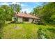Quaint single-story house with a red metal roof, surrounded by green lawns, landscaping and mature trees at 680 Unity Church Rd, Morgantown, IN 46160