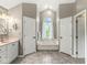 A bathroom with a garden tub under a window and gray tile flooring at 6818 Bluffridge Dr, Indianapolis, IN 46278