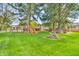 Large backyard with a play structure, mature trees, and outdoor seating area at 695 W Clinton St, Danville, IN 46122