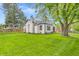 Charming white home with black trim and a lush green lawn, surrounded by mature trees and blue skies at 695 W Clinton St, Danville, IN 46122
