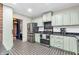 Well-lit kitchen with stainless steel appliances, mosaic tile floor, and light green cabinets at 695 W Clinton St, Danville, IN 46122