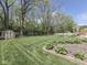 Beautifully landscaped backyard with manicured lawn, flower beds, mature trees, and a charming swing set area at 748 Woodcreek Ct, Greenwood, IN 46142