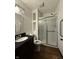 Bathroom featuring a dark vanity, shower with glass doors, modern fixtures, and wood-look flooring at 7627 Venetian Way, Indianapolis, IN 46217