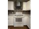Close up of the kitchen with white cabinets, range, vent hood, and tile backsplash at 7627 Venetian Way, Indianapolis, IN 46217