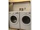 Laundry room with white washer and dryer, functional shelving, and tile flooring for convenience at 7627 Venetian Way, Indianapolis, IN 46217