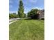 Spacious front yard with lush green grass and mature trees lining the street under a blue sky at 8306 Hunters Meadow Way, Indianapolis, IN 46259