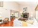 Open living room with vaulted ceiling, brick fireplace, wood floors, and access to the dining area at 8980 Cinnebar Dr, Indianapolis, IN 46268