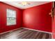 Bedroom with vibrant red walls, wood-look flooring, and a window offering natural light at 925 Mallory Pkwy, Franklin, IN 46131