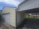 A yellow garage with a white door sits next to a carport, offering both covered parking and storage space at 1131 S Pershing Ave, Indianapolis, IN 46221