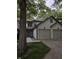 Two-story home with a two-car garage and neutral siding surrounded by mature trees and lush landscaping at 11506 Hidden Bay, Indianapolis, IN 46236