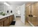 Bathroom with double sinks, vanity with wood cabinets, and a separate tiled shower with glass door at 13094 Overview Dr # 5D, Fishers, IN 46037