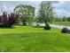Expansive backyard featuring lush lawn, mature trees, and a tranquil pond with picnic table at 14058 Southwood Cir, Fishers, IN 46037
