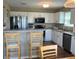 Modern kitchen featuring white cabinets, stainless steel appliances, breakfast bar, and warm wood-look floors at 14058 Southwood Cir, Fishers, IN 46037