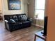 Cozy living room with dark wood floors features a black leather sofa and modern decor at 14058 Southwood Cir, Fishers, IN 46037