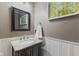 Elegant powder room with a granite vanity, wainscoting, and a decorative mirror at 1783 Trillium Ct, Avon, IN 46123