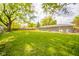 Generous backyard with lush lawn, mature trees, shed, and house exterior, offering privacy and space for various activities at 2319 E 40Th St, Anderson, IN 46013