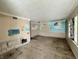 A damaged living room featuring bare floors, damaged walls, and a single window letting in natural light at 2337 N Webster N Ave, Indianapolis, IN 46219
