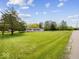 Large green yard with mature trees, leading to a single story home at 2399 E Mckay Rd, Shelbyville, IN 46176