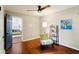 Cozy bedroom featuring hardwood floors, a ceiling fan, and comfortable seating area with views to living room at 253 E Minnesota St, Indianapolis, IN 46225