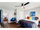 Well-lit bedroom featuring a ceiling fan, colorful decor, and access to another room at 253 E Minnesota St, Indianapolis, IN 46225
