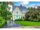 Charming Tudor-style home with a manicured lawn, mature trees, and a vibrant blue front door at 329 W Hampton Dr, Indianapolis, IN 46208