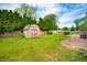 Backyard featuring a storage shed, lush green grass, wooden fence, and manicured bushes at 3505 Autumn Ct, Columbus, IN 47203