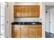 Close-up of wet bar with wood cabinets, dark granite countertop, stainless steel sink and fixtures at 355 E Ohio St # 314, Indianapolis, IN 46204