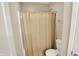 Neutral-toned bathroom featuring a bathtub with a closed beige shower curtain and a white toilet at 4602 Amesbury Pl, Westfield, IN 46062