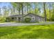 Cozy home with a gravel driveway, wooden porch, and garage surrounded by mature trees at 5039 Five Points Rd, Indianapolis, IN 46239