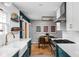 An open kitchen with white countertops, teal cabinets, stainless steel appliances, and a view into the dining area at 5439 Indianola Ave, Indianapolis, IN 46220