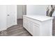 Bright kitchen island with white cabinets and gray wood grain floors with pantry and stairway views at 5784 Summertree Pl, Whitestown, IN 46052