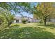 Spacious backyard with green grass, patio area, white home exterior, and mature trees at 6613 Apollo Way, Indianapolis, IN 46278