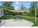 Backyard patio featuring a shade covering, outdoor dining set, manicured lawn, and lush landscaping for peaceful outdoor enjoyment at 6825 Farmleigh Dr, Indianapolis, IN 46220