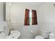 Bright bathroom featuring a sink, toilet, and a window with patterned curtains at 6825 Farmleigh Dr, Indianapolis, IN 46220