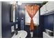 Cozy bathroom with stylish blue walls, vanity, and patterned curtain at 6825 Farmleigh Dr, Indianapolis, IN 46220