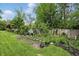 Lush backyard featuring a stone pathway and beautiful landscaping, set against a backdrop of a wooden fence and mature trees at 6825 Farmleigh Dr, Indianapolis, IN 46220