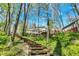 The backyard has lush greenery leading to home and deck, with natural log steps weaving through the trees at 8820 Mud Creek Rd, Indianapolis, IN 46256