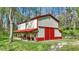 Exterior view of a barn featuring red trim and doors, set amidst a tranquil grassy landscape surrounded by trees at 8820 Mud Creek Rd, Indianapolis, IN 46256