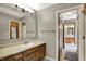Full bathroom with wood cabinets, solid countertop, large mirror, and an open doorway to additional bathrooms at 8820 Mud Creek Rd, Indianapolis, IN 46256