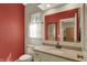 Powder room featuring red accent wall, toilet, vanity, and window at 8820 Mud Creek Rd, Indianapolis, IN 46256