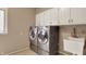 Bright laundry room with stainless steel washer and dryer set, utility sink and overhead storage at 8820 Mud Creek Rd, Indianapolis, IN 46256