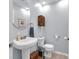 Stylish powder room featuring a pedestal sink, round mirror, and wood accents at 9860 Sunnymeade Ln, Indianapolis, IN 46280