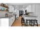 Open kitchen features white cabinets, stainless steel appliances, gray counters, hardwood floors, and barstool seating at 9860 Sunnymeade Ln, Indianapolis, IN 46280