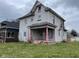 Two story home with covered porch, showing peeling paint and overgrown yard at 1014 W 33Rd St, Indianapolis, IN 46208
